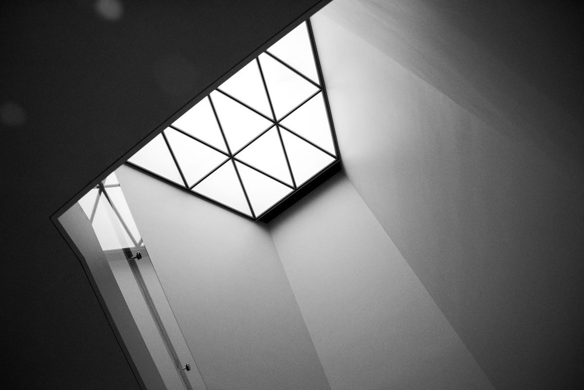 Skylight with triangular panes letting daylight into a white ceiling shaft